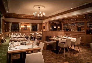 Ein elegantes Restaurant mit Holzmobiliar und sanfter Beleuchtung. Die Tische sind ordentlich gedeckt und es herrscht eine gemütliche Atmosphäre.