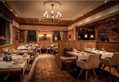 Ein stilvolles Restaurant mit holzgetäfelten Wänden und eleganten Tischdeko. Sanfte Beleuchtung schafft eine einladende Atmosphäre.