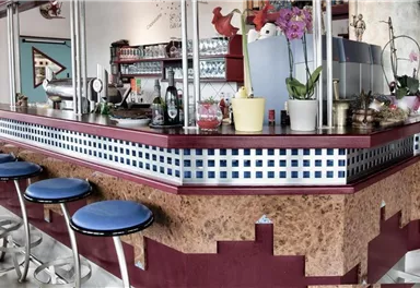 A stylish bar with blue stools and colorful decorations. The counter is designed in a modern style and offers an inviting atmosphere.