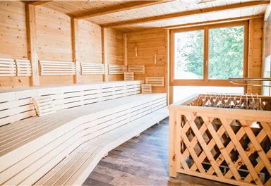 A bright wellness room with wooden benches and large windows. The room radiates tranquility and relaxation.