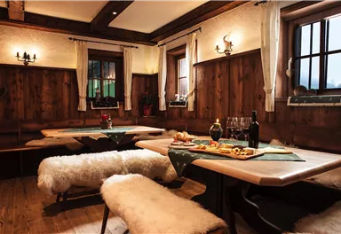 A cozy room with wooden elements and warm light. Drinks and snacks are on the tables, surrounded by an inviting atmosphere.