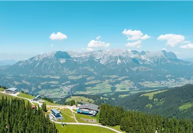 An impressive mountain landscape with green meadows and hills. The clear sky and clouds provide a picturesque view.