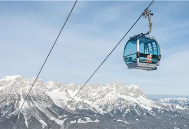 Eine Seilbahn schwebt über schneebedeckte Berge. Der klare Himmel und die majestätische Landschaft vermitteln ein Gefühl von Freiheit.