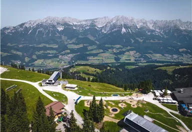 A picturesque mountain landscape with green meadows and dense forests. The impressive mountains in the background create a beautiful backdrop.