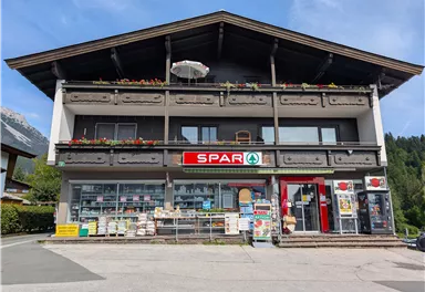A two-story building with the SPAR logo. There are windows and a sales area with various products on the ground floor.