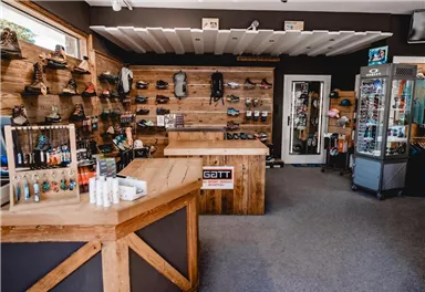 A sporting goods store with wooden shelves displaying various shoes and equipment. Care products and small accessories are on the counter.