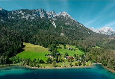 A picturesque landscape with high mountains and green meadows. A clear lake reflects the beauty of nature.