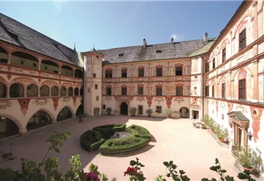 A historic courtyard with intricately decorated walls and a central garden. The architecture showcases a unique, traditional style.