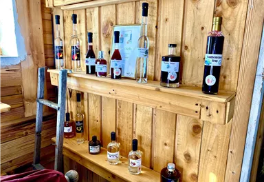 A wooden shelf wall with various bottles of liqueurs and spirits. The bottles are well organized and offer a variety of colors and labels.