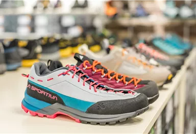 Colorful sports and hiking shoes are displayed on a table. The shoes have various designs and are suitable for outdoor activities.