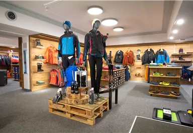 A sporting goods store with outdoor clothing and equipment. Two mannequins showcase functional sportswear in a modern sales area.