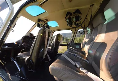 An interior of a helicopter with several seats. The seats are comfortable and equipped with safety belts.
