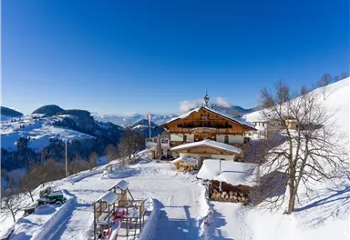 A cozy mountain house surrounded by snow-covered landscapes. The clear blue sky complements the wintry atmosphere.