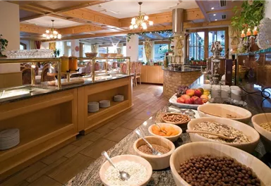 Ein einladendes Buffet mit verschiedenen Frühstückszutaten wie Cerealien, Nüssen und frischem Obst. Der Raum ist hell und freundlich, mit einem rustikalen Ambiente.