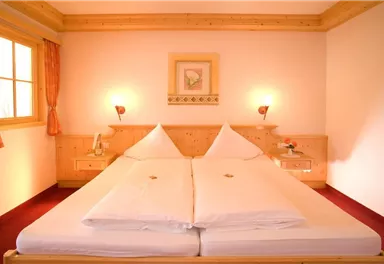 Ein gemütliches Schlafzimmer mit einem großen Doppelbett und Holzdekor. Das Zimmer ist hell erleuchtet und hat ein Fenster mit Aussicht.