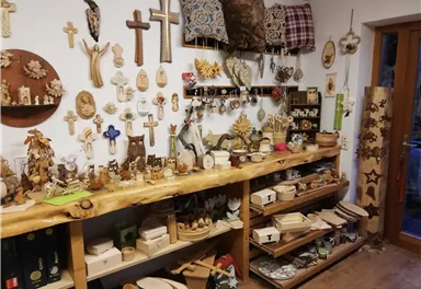 Ein Raum mit vielen handgefertigten Holzobjekten und Dekorationen. Regale und Wände sind mit Holzschnitzereien, Kissen und anderen Kunstwerken dekoriert.