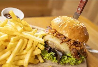 A juicy burger with a crispy topping and fresh vegetables. Served with golden-brown French fries.