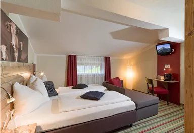 Ein gemütliches Zimmer mit zwei Betten, modernen Möbeln und einem Fernseher. Die Atmosphäre ist hell und freundlich, ideal für Entspannung.