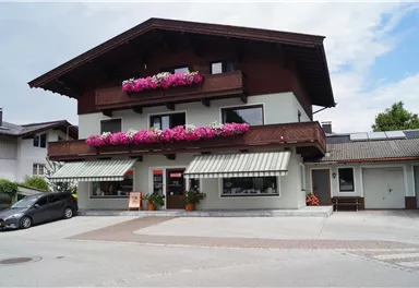 Ein charmantes, traditionelles Gebäude mit Blumenkästen und Terrassen. Die umliegende Umgebung ist ruhig und einladend.