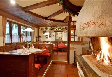 A cozy restaurant with wooden furniture and an open fireplace. The warm colors and the loving decoration create an inviting atmosphere.