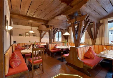 A cozy restaurant with rustic wooden furniture and warm colors. The tables are set for guests and flowers adorn the surroundings.