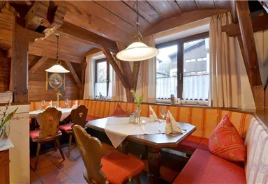 A cozy restaurant with wooden decor and an inviting seating nook. The table is lovingly set, and the atmosphere is warm and welcoming.