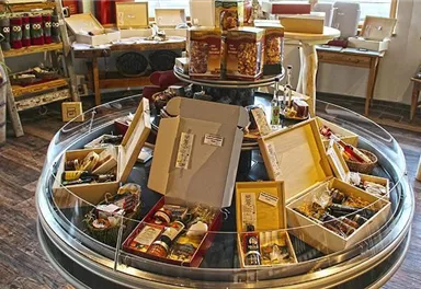 Ein runder Tisch mit verschiedenen Geschenkboxen und Delikatessen. Die Atmosphäre ist einladend und gemütlich.