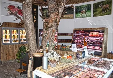Ein gemütlicher Metzgereibereich mit Holzdekoration und einer großen Auswahl an Fleischprodukten. In der Mitte steht ein Baum, der das rustikale Ambiente betont.