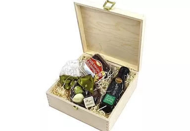 Eine schöne Geschenkkiste mit verschiedenen Delikatessen, darunter Olivenöl, Pralinen und Snacks. Die Kiste ist mit Holzwolle gefüllt und hat einen dekorativen grünen Bow.