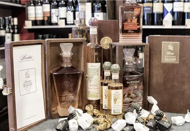 An elegant presentation of various spirits bottles in stylish packaging. In the background, wine bottles are arranged, creating a cozy atmosphere.