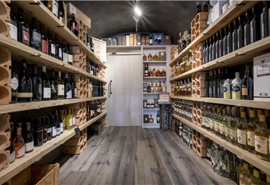 A well-organized wine cellar with shelves full of bottles. The walls are equipped with wooden shelves that showcase different varieties of wine.