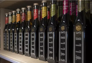 A row of bottles filled with high-quality oil in various colors on a shelf. Each bottle features an elegant design and eye-catching labels.