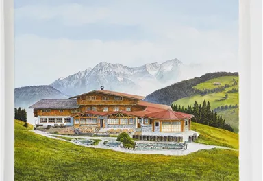 A large, picturesque wooden house in a green hill and mountain landscape. The scene shows clear skies and surrounding forests.