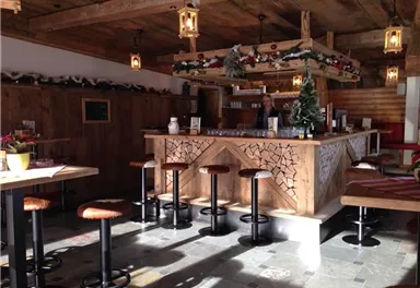 A cozy bar with wooden decor and tall chairs. The interior is rustic and festively decorated.