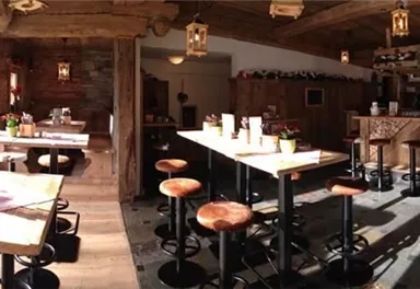 A cozy restaurant with rustic decor and wooden tables. The atmosphere is warm and inviting, with plenty of light from the windows.