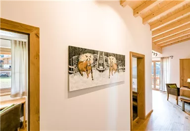 A bright interior with wooden ceilings and two doors.  
On the wall hangs a painting of two horses in the snow.