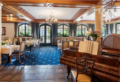 A cozy restaurant with elegant decor and large windows. Tables are decorated with white tablecloths and flowers.