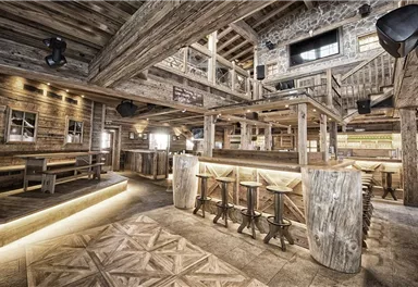 A rustic interior view of a cozy restaurant with wooden decor. The atmosphere is inviting and modern, with lighting and comfortable seating areas.