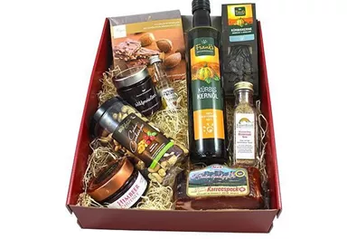 Ein Geschenkkorb mit verschiedenen Delikatessen, darunter Öl, Gewürze, Nüsse und Süßigkeiten. Der Korb ist schön dekoriert und eignet sich hervorragend als Geschenk.