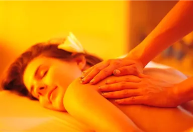 A relaxing massage in warm, gentle light. A woman is enjoying the treatment and looks very relaxed.