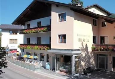 Ein gemütliches Café mit Blumenbalkonen und sonnigen Terrassen. Die Umgebung ist malerisch und einladend.