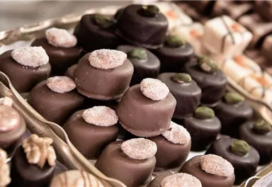 A selection of artistically decorated chocolates on a silver tray. The chocolate has various shapes and toppings that catch the eye.
