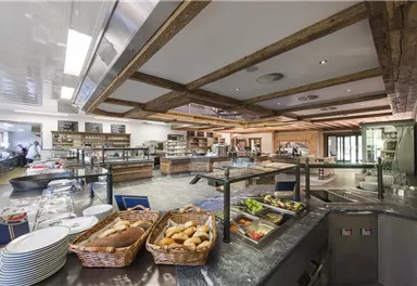 A modern, inviting kitchen with wood and glass elements. The reception counter is decorated with fresh produce and baked goods.