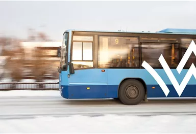 Ein blauer Bus fährt auf einer verschneiten Straße. Die Anzeige zeigt die Linie 9.