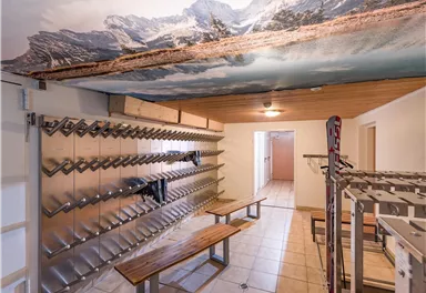 A room with a mountain motif on the ceiling and spacious benches. There are metal shelves on the walls for storing equipment.