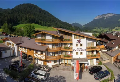 A cozy hotel amidst green hills and mountains. The clear sky and the inviting atmosphere create a perfect holiday destination.