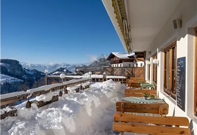 A beautiful mountain landscape with snow-covered terraces and blue sky. The wooden chairs invite you to relax.