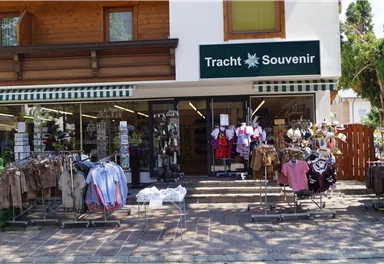 Ein Geschäft mit Trachten und Souvenirs. Vor dem Laden stehen Kleiderständer mit traditioneller Kleidung.