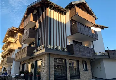 A modern building with wooden cladding and balconies. The façade is inviting and stylishly designed.