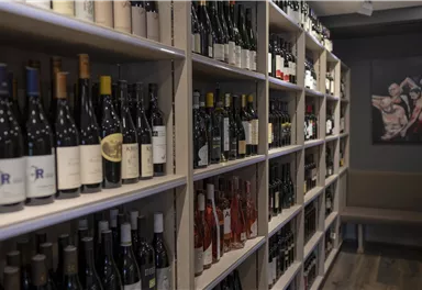 A well-organized wine cellar with shelves full of wine bottles. In the background, a modern wall decoration is visible.